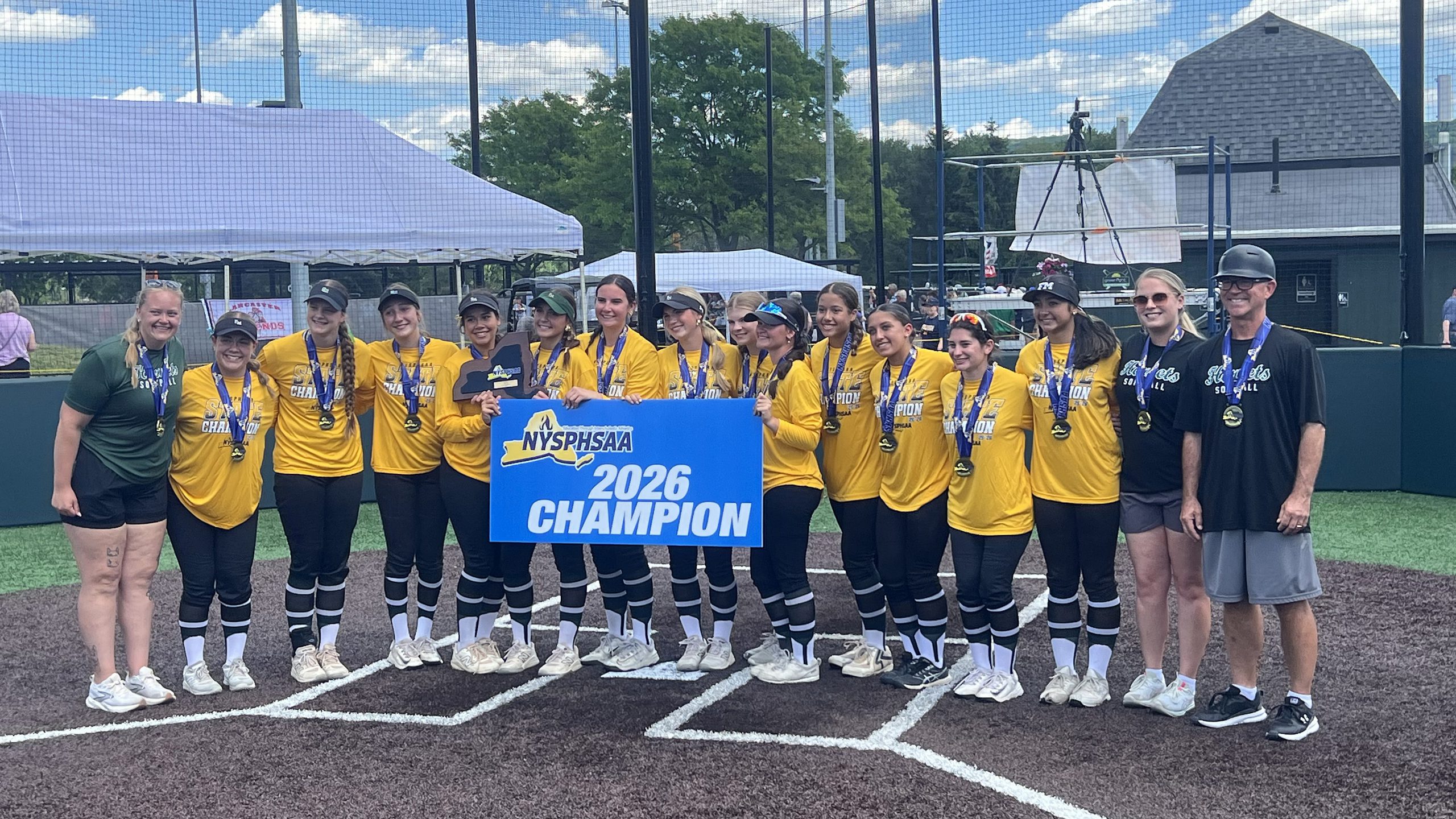 Softball team standing in a group holding a banner that says 2026 Champion