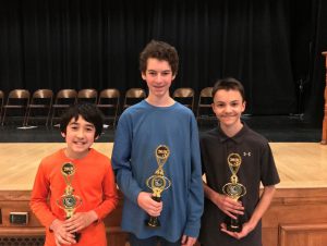Three boys holding trophies. 