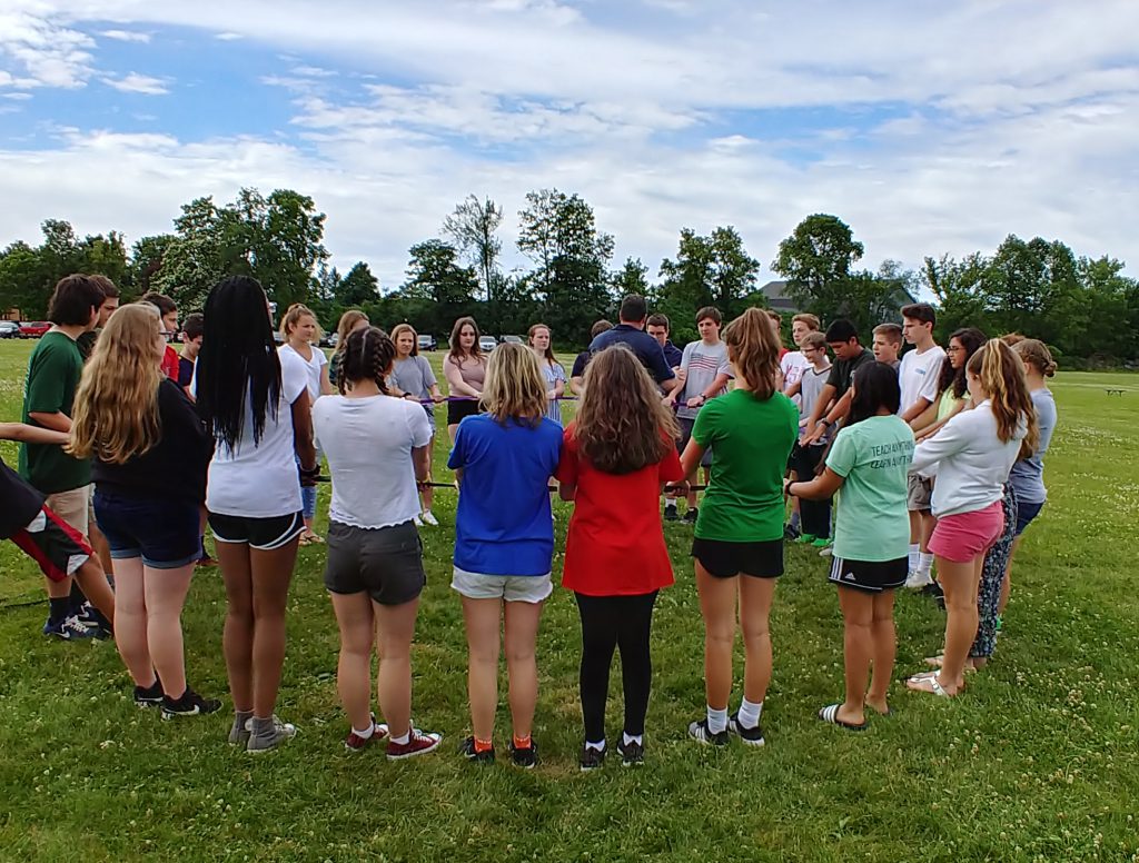 Students standing in a circle participating in a team-building exercise.