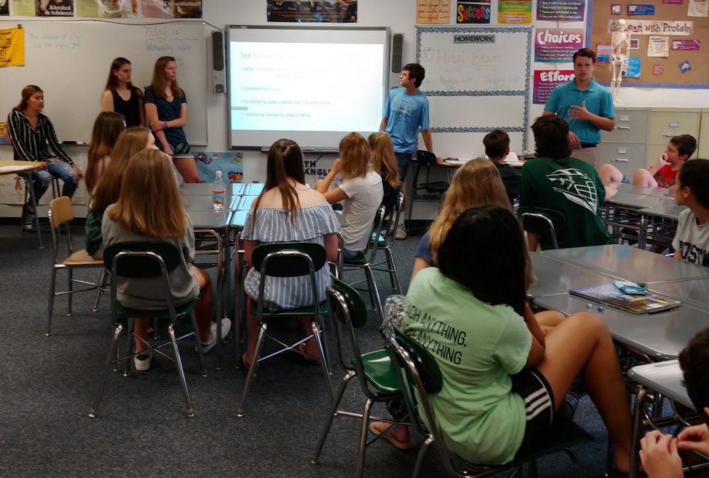 Eighth grade students sitting at desks in a classroom listening to a presentation.