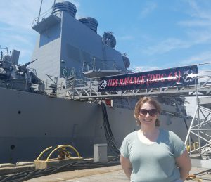 This is an image of Melissa Asztalos standing in front of the USS Ramage.