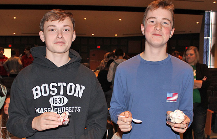 This is an image of two boys smiling for the camera and holding ice cream