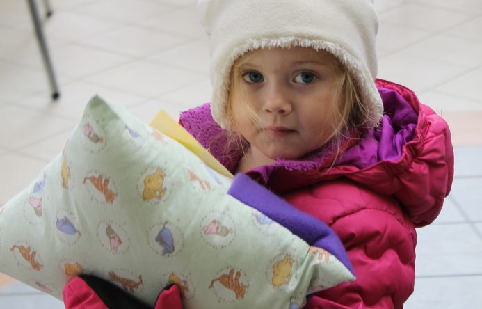 This is an image of a young student holding a pillow