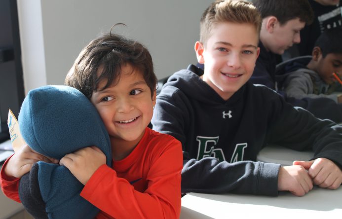 This is an image of a young student hugging a pillow