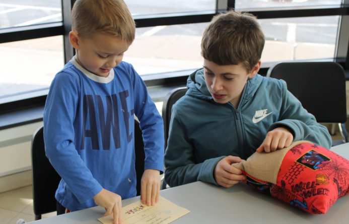 This is an image of a young student opening a memory book while sitting next to an older student