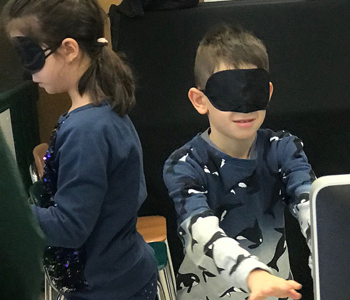 This is an image of two elementary school students wearing blindfolds