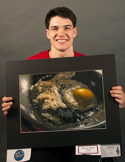 This is an image of an F-M student holding his artwork