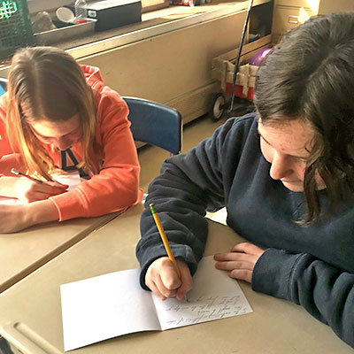 This is an image of two students writing cards