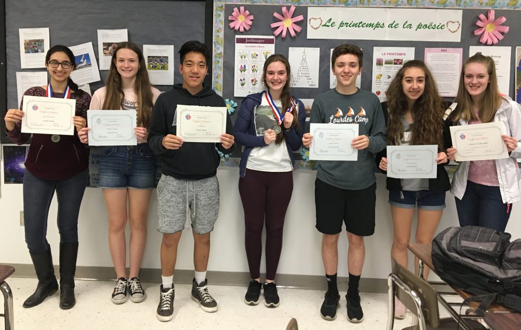 A group of students stand holding paper certificates. 