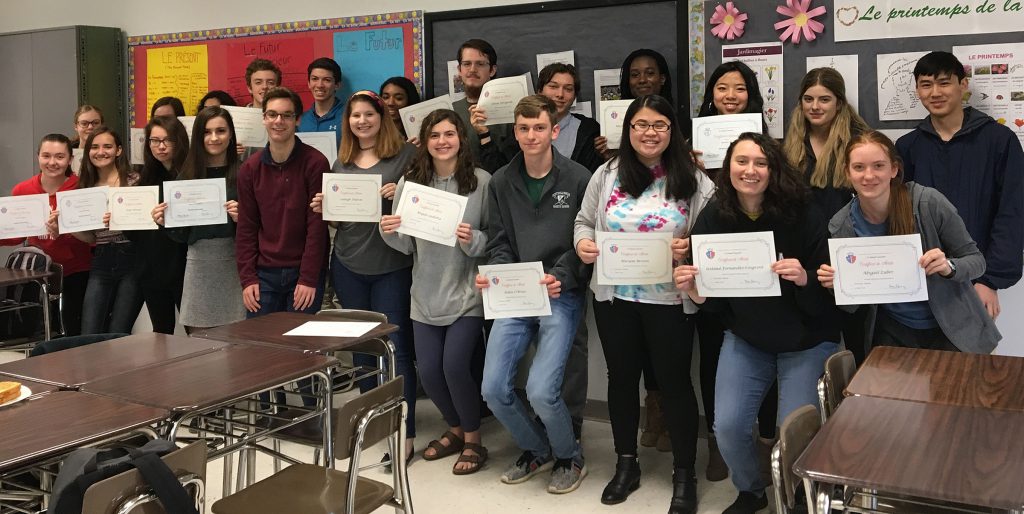 A group of students stand holding paper certificates. 