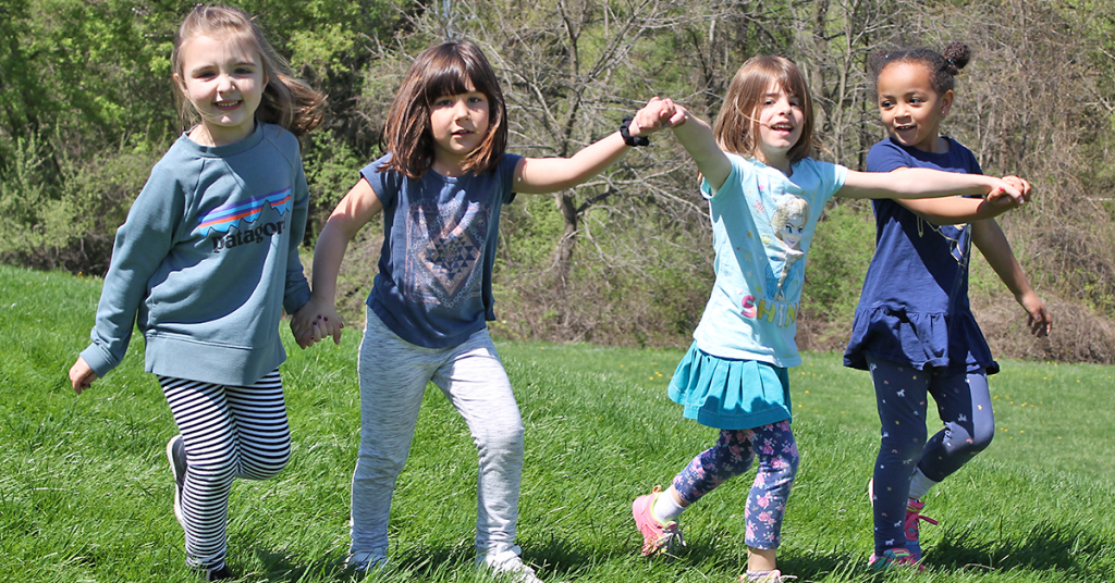 This is an image of students holding hands and walking through grass