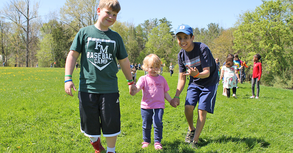 This is a photo of two students walking with a small child