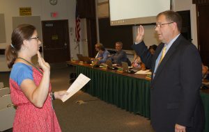 A man and woman facing each other with their right hands raised. 