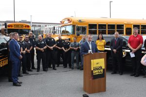 Man standing at podium with police officers gathered behind him.