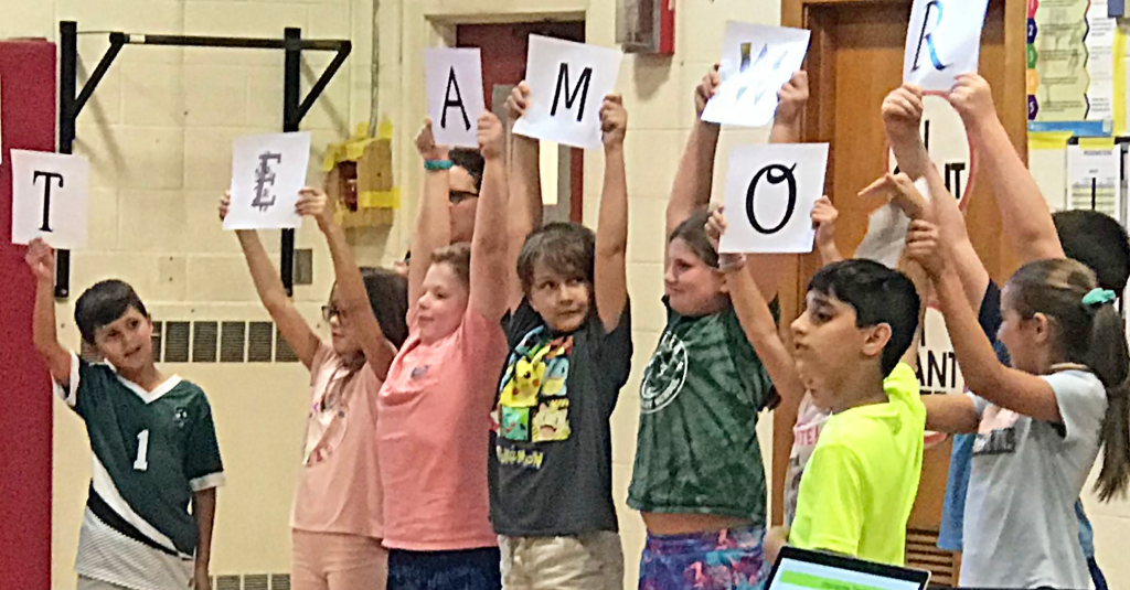 This is an image of students holding up a teamwork sign