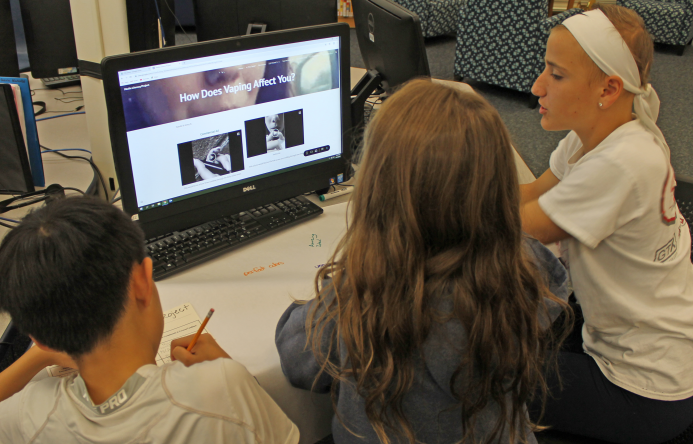 This is an image of three students sitting around a computer