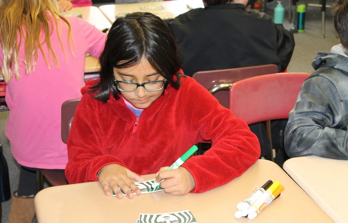 Girl seated at desk coloring.