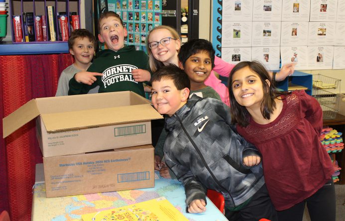 Group of students standing by a cardboard box.