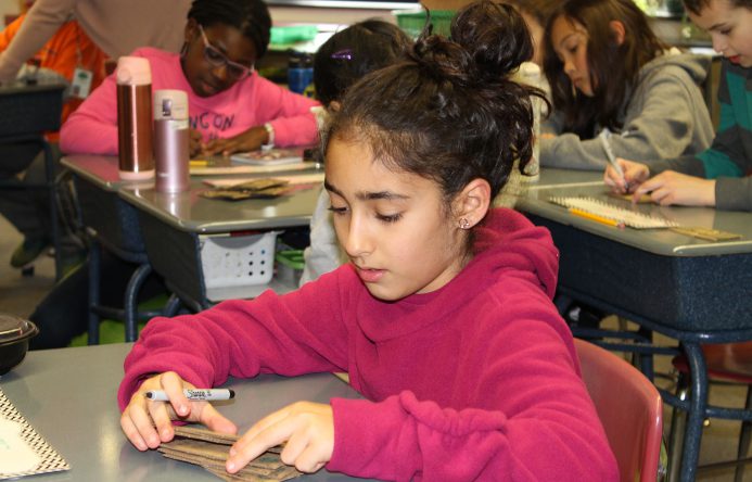 Girl seated at desk writing.