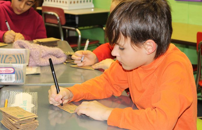 Boy seated at desk writing.