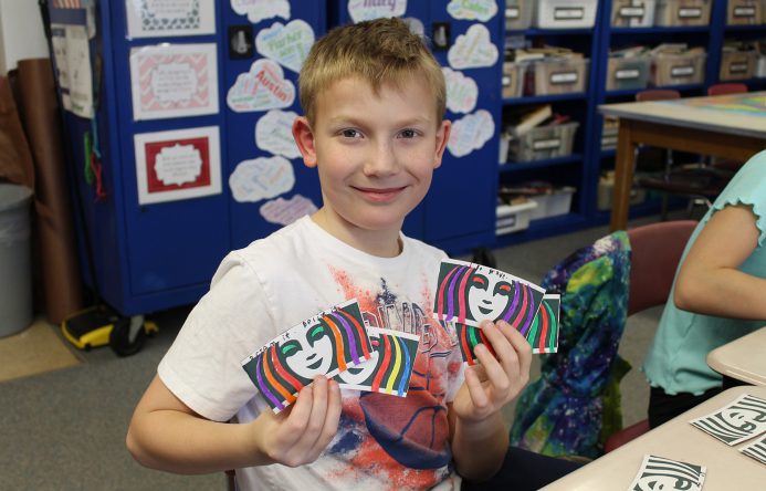 Boy holding up colored coffee sleeves.