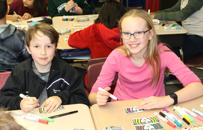 Girl and boy seated at desk coloring.