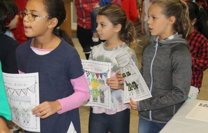 Students walking in hallway, holding signs.