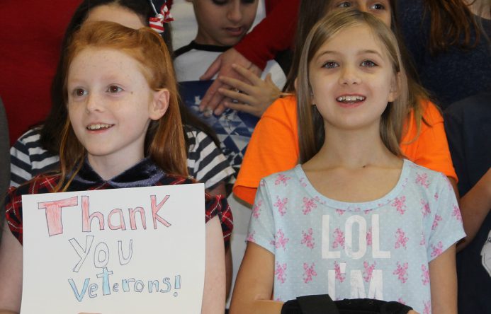 Girl holding "Thank you Veterands" sign, left, girl smiling, standing, right