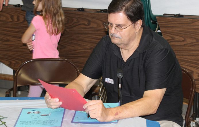 Man seated at table reading a letter.