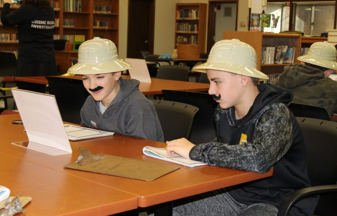 Tow boys wearing safari hats seated at table.