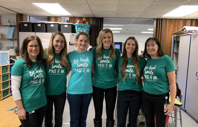 Group of women standing in a line, all wearing the same t-shirt.