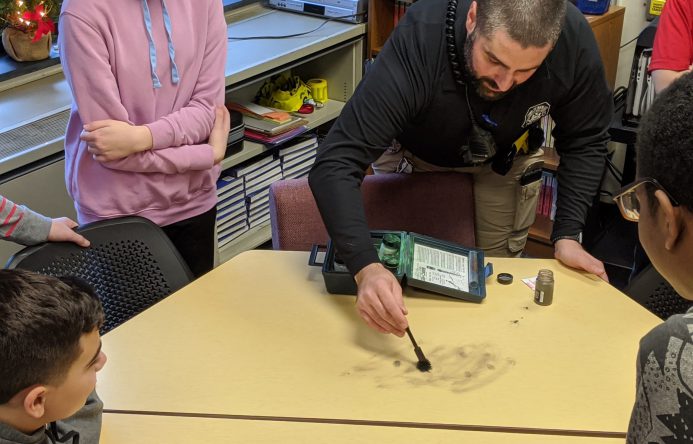 Officer Filip dusting table for fingerprints.