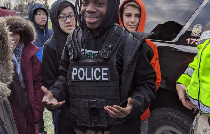 Student wearing police helmet and vest.