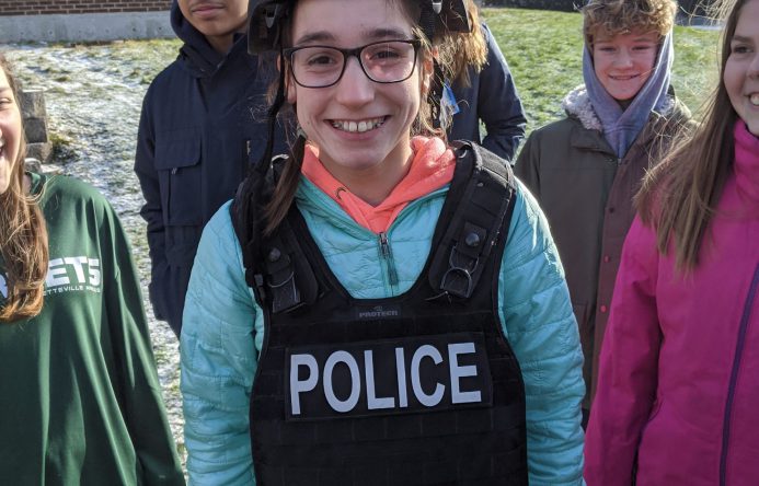 Student wearing police helmet and vest.