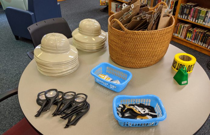 Safari hats, magnifying glasses and other accessories laid out on table.