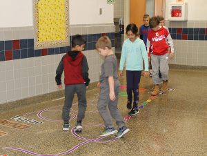 Students walking on sticker path in hallway.