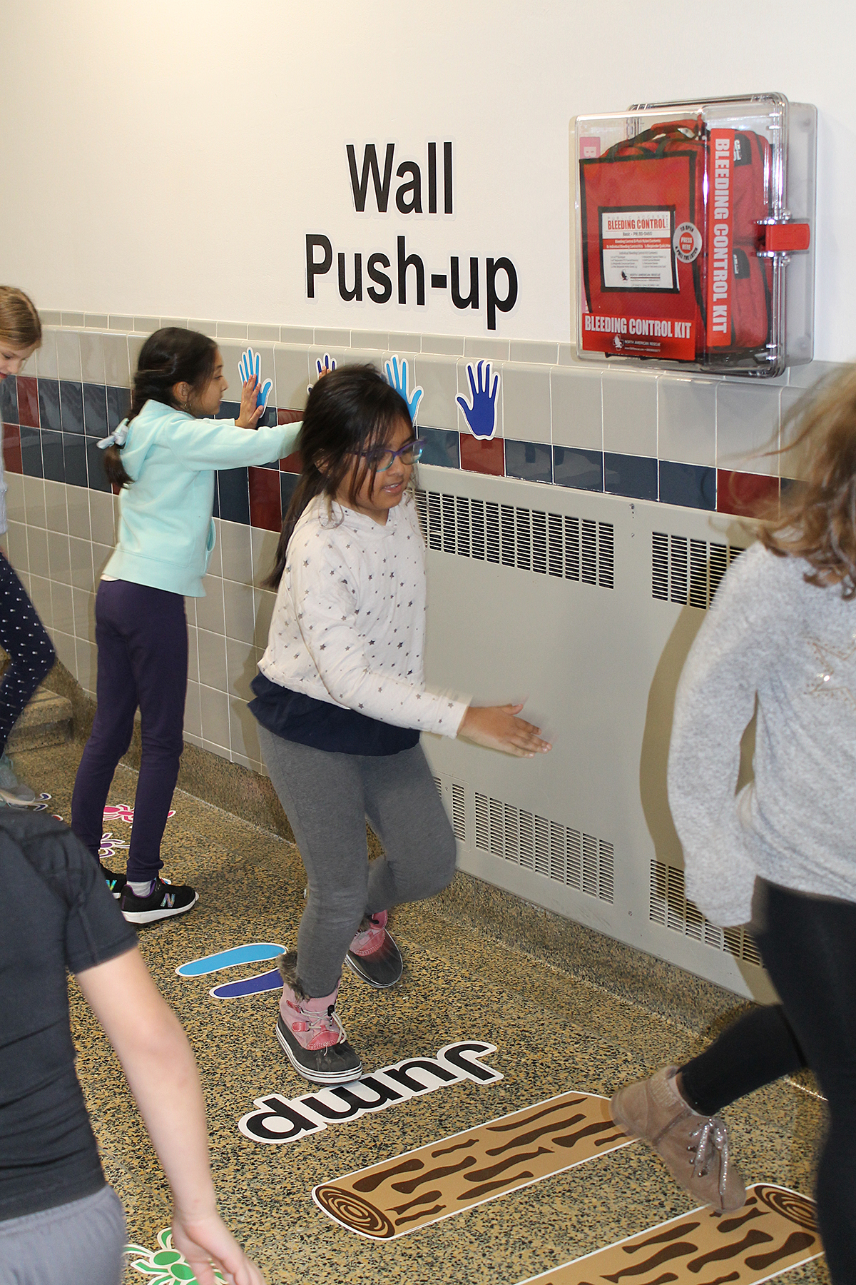 Students hopping on sticker path in hallway.