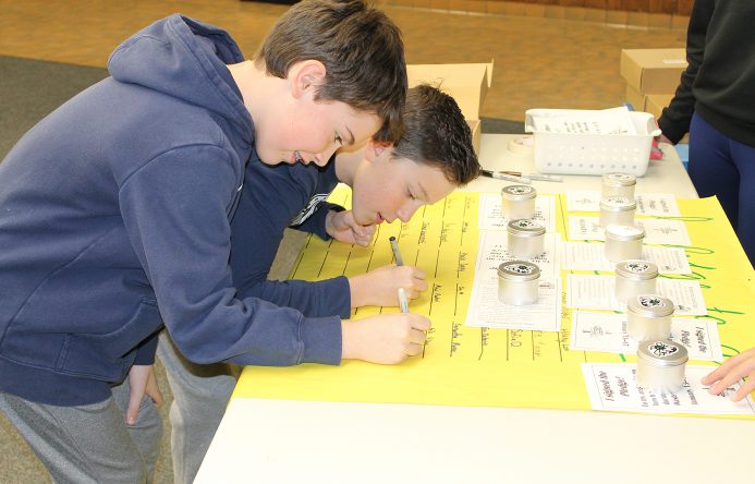 Two students signing pledge sheet.