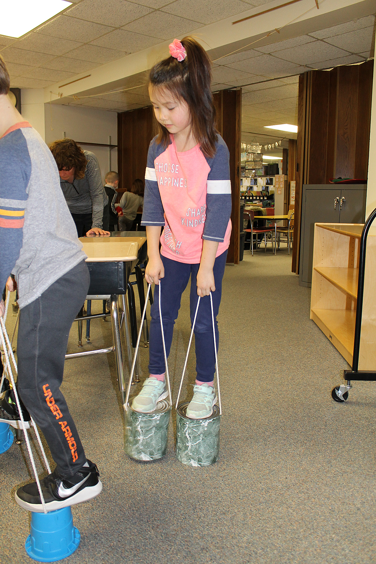 Student standing on paint cans.