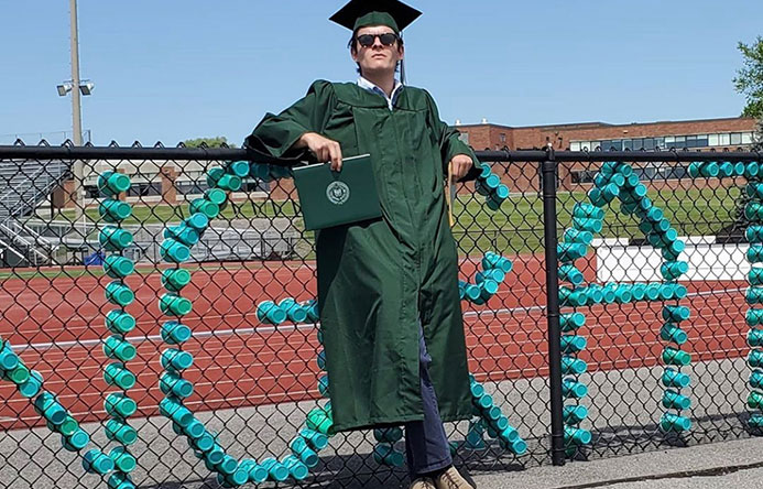 This is an image of a graduate standing next to a fence