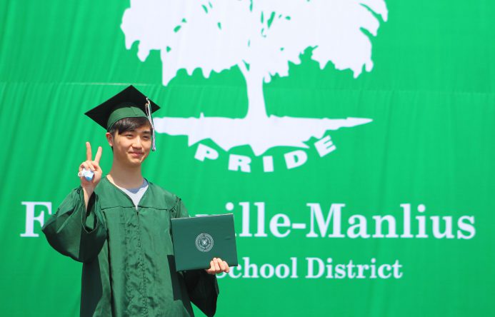 This is an image of a graduate making the peace sign