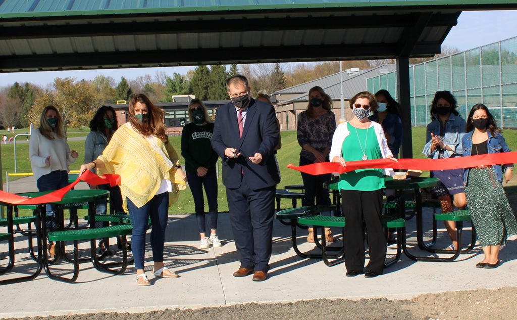 Group of people with red ribbon cut in half falling in front of them.