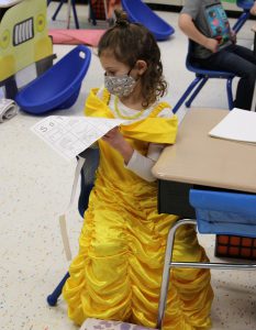 student seated at desk wearing yellow princess dress. 