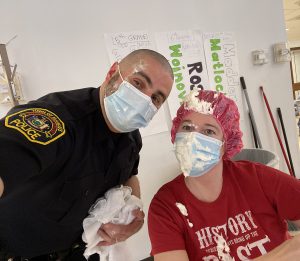 Two people wearinig face masks with traces of whipped cream on their faces lean together.