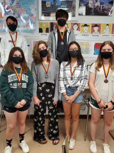 Students standing side-by-side in a group wearing face masks.