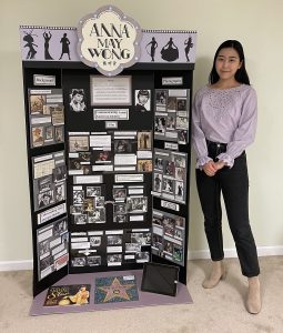 Student standing next to poster display.