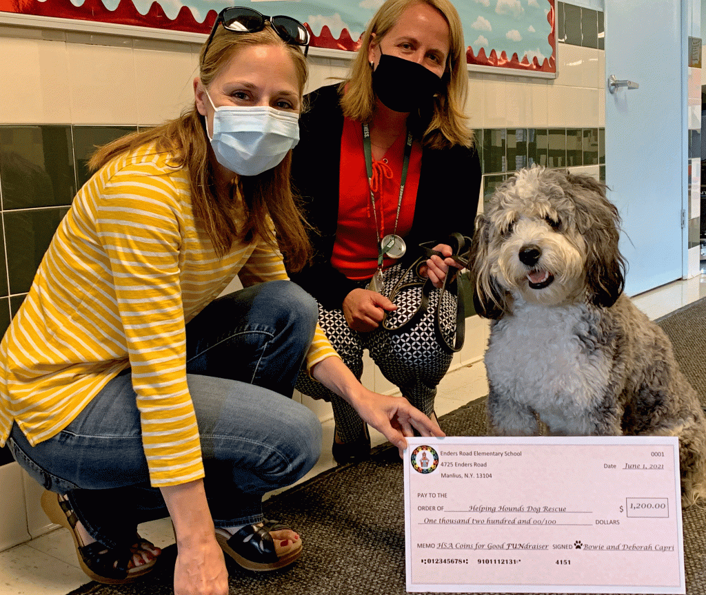 This is an image of Enders Road Principal Deborah Capri kneeling down with the school's HSA president and therapy dog