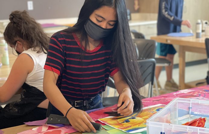 Student attaching squares to cardboard.