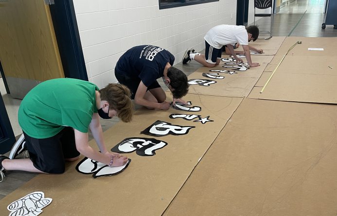 Students tracing mural design on cardboard.