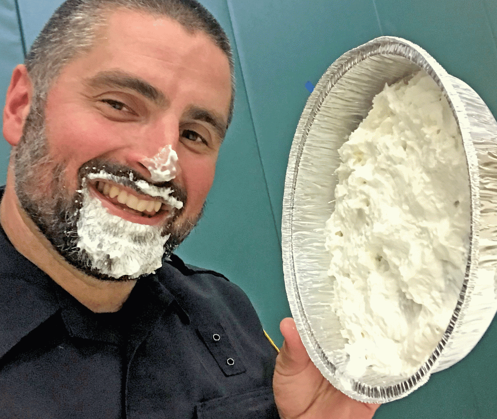 This is an image of School Information Resource Officer Dan Filip holding a whipped cream pie